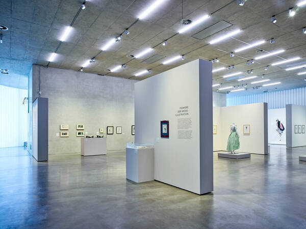 Weite Ausstellungsansicht mit Kleidern und Modeillustrationen in der Galerie Stihl Waiblingen